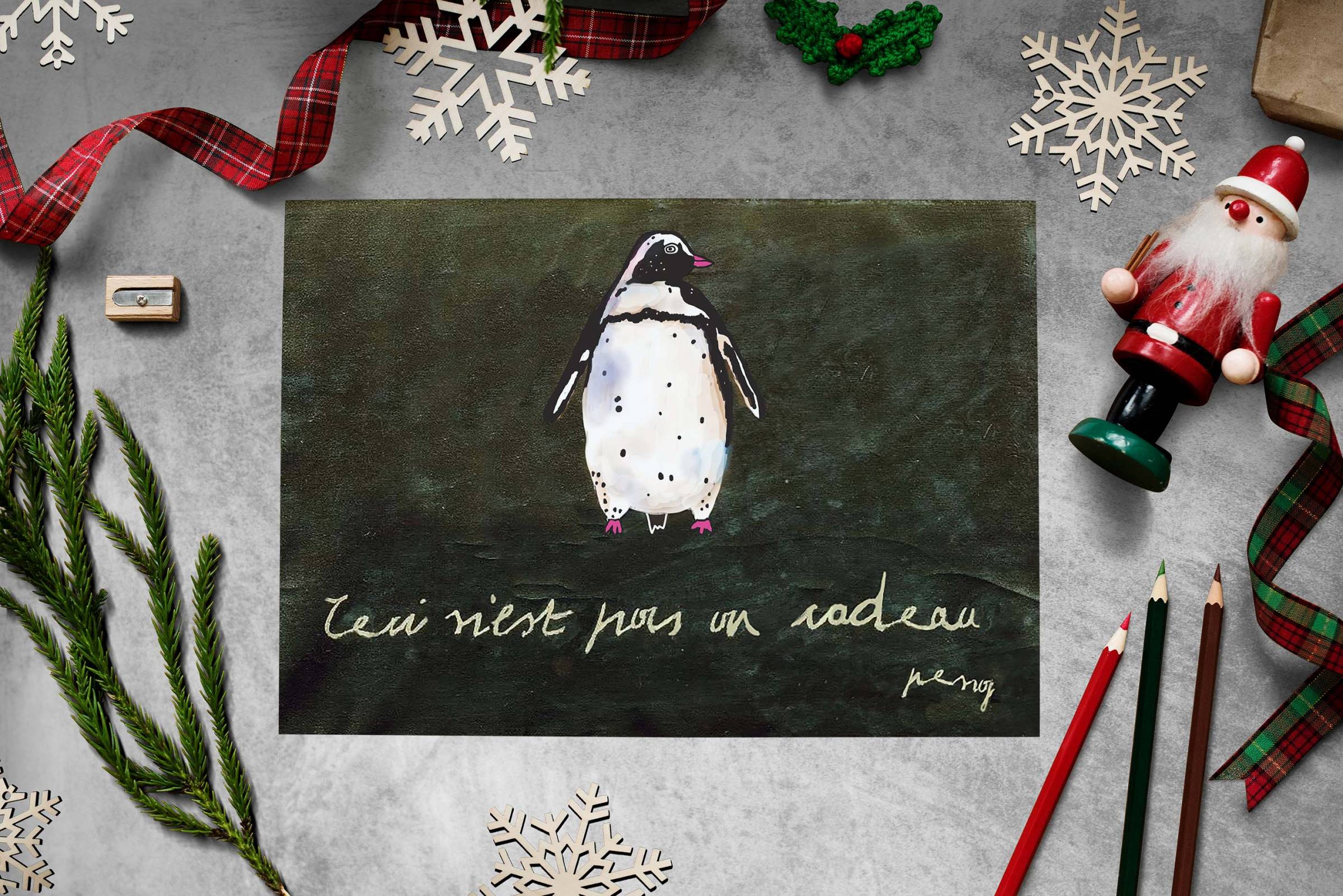 Postkarte mit Pinguinmotiv auf einem Tisch mit Weihnachtsdeko liegend
